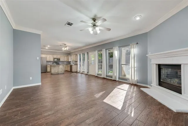 a view of a livingroom with wooden floor a ceiling fan and windows