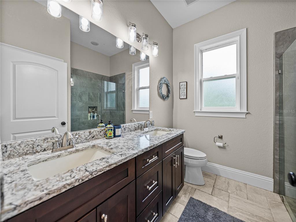 3985 Mammoth Grove Road Lake Wales, FL 33898 - Photo 52 of 97 a bathroom with a granite countertop sink a toilet and a mirror