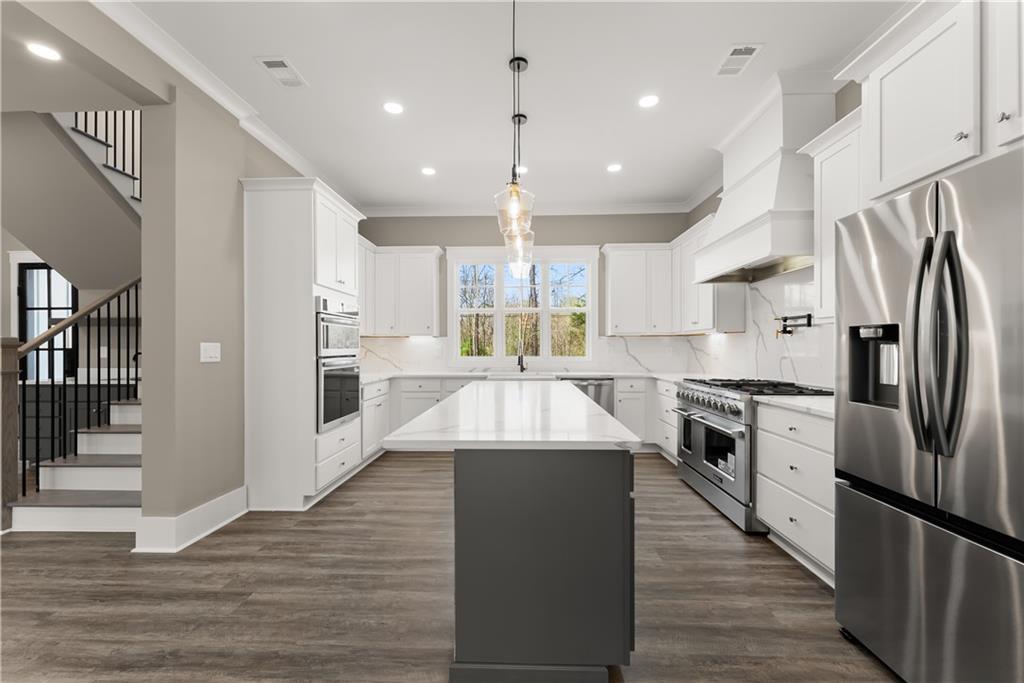 5697 Ball Ground Road Ball Ground, GA 30107 - Photo 8 of 63 a large kitchen with stainless steel appliances kitchen island granite countertop a stove a refrigerator and a view of living room