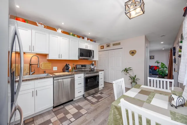 a kitchen with stainless steel appliances granite countertop a stove top oven a sink dishwasher and a dining table with wooden floor