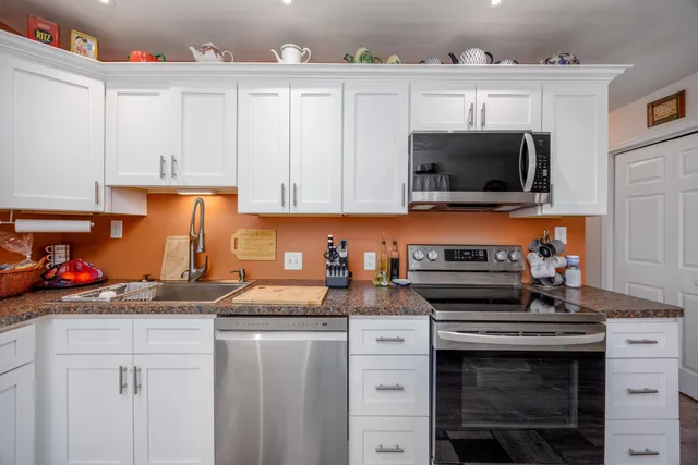 a kitchen with granite countertop a stove top oven a sink dishwasher and cabinets with wooden floor