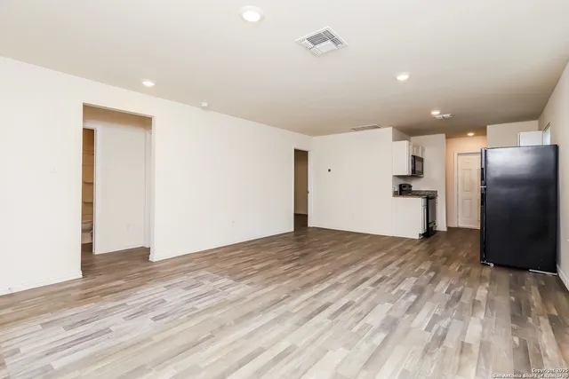 a view of a kitchen with refrigerator and wooden floor