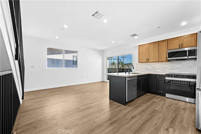 a kitchen with a sink a counter top space stainless steel appliances and cabinets