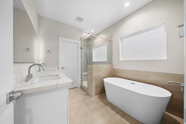 a bathroom with a white tub a sink and a mirror