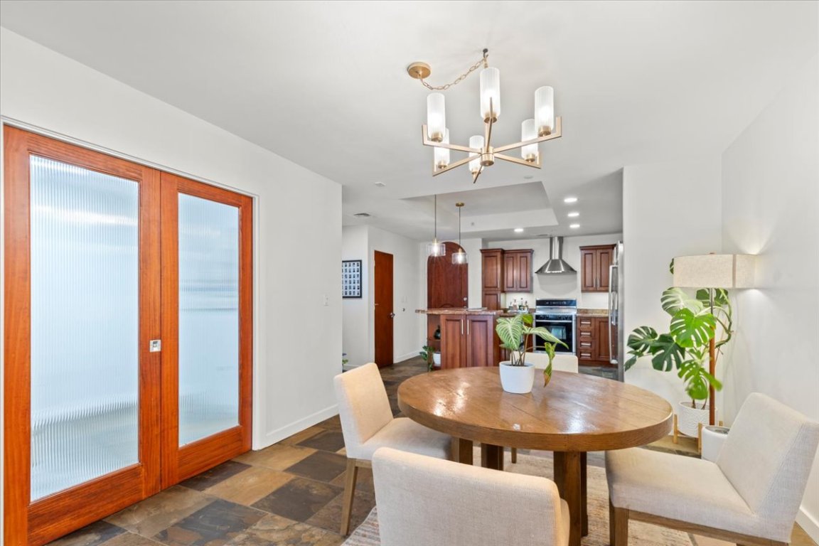 1812 West Avenue, Unit 306 Austin, TX 78701 - Photo 21 of 38 Dining space featuring stone finish floor, a chandelier, and baseboards