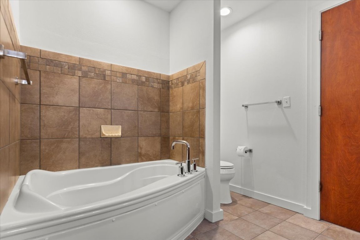 1812 West Avenue, Unit 306 Austin, TX 78701 - Photo 33 of 38 Full bath featuring toilet, a bath, tile patterned floors, and baseboards