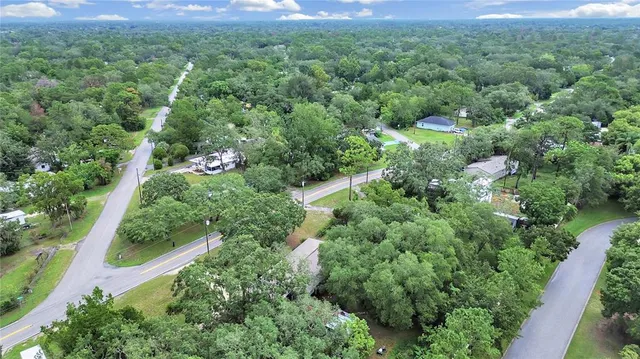 an aerial view of residential house with outdoor space and trees all around