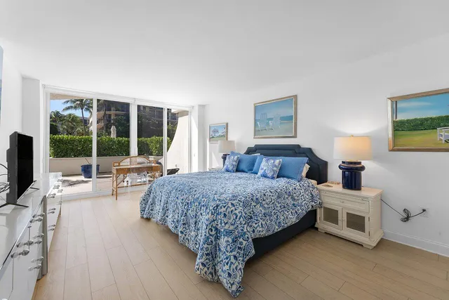 a living room with a bed furniture large window and a flat tv screen