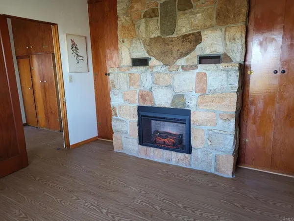 an empty room with wooden floor a fireplace and entryway