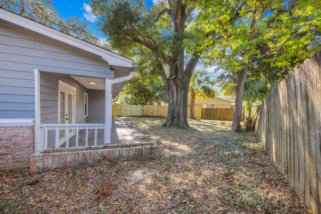 a backyard of a house with large trees and brick wall