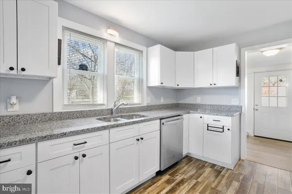 a kitchen with granite countertop white cabinets and a window