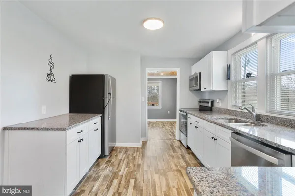 a kitchen with granite countertop a sink stove and refrigerator