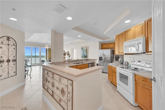 a kitchen with stainless steel appliances granite countertop a stove top oven a sink a refrigerator and white cabinets with wooden floor