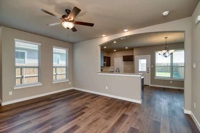 a view of an empty room with window and wooden floor