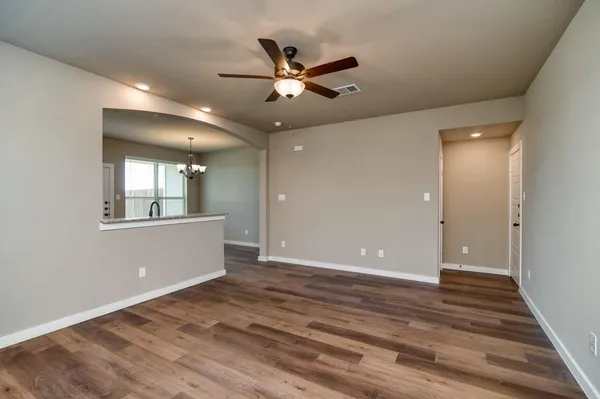 a view of an empty room with window and wooden floor