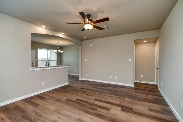 a view of an empty room with window and wooden floor