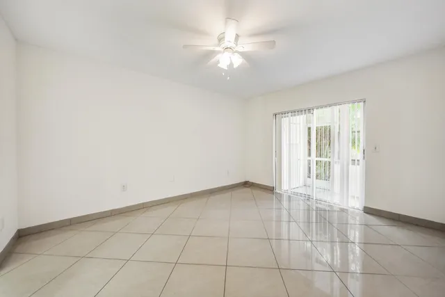 an empty room with a ceiling fan and carpet