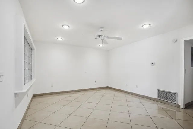 an empty room with white walls and ceiling fan