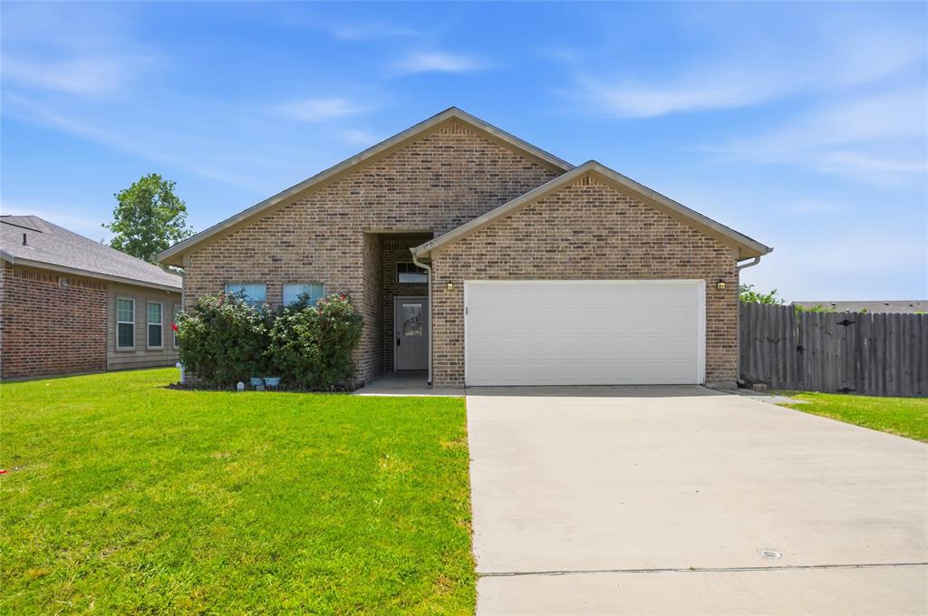 Brick facade residence featuring a front entry, covered porch, attached two-car garage, concrete driveway, and established front landscaping