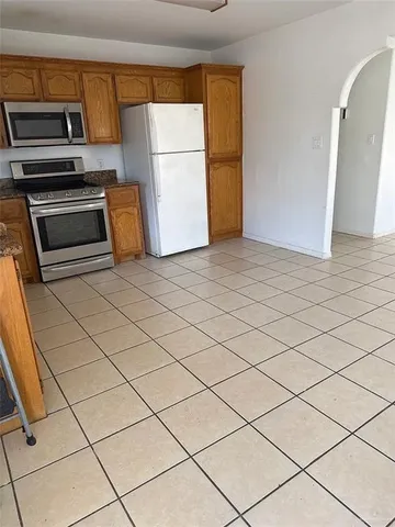 a kitchen with granite countertop a refrigerator and a stove top oven