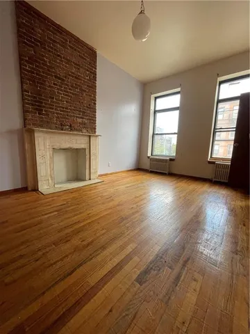 a view of an empty room with window and wooden floor