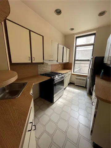 a kitchen with a sink a stove top oven and cabinetry
