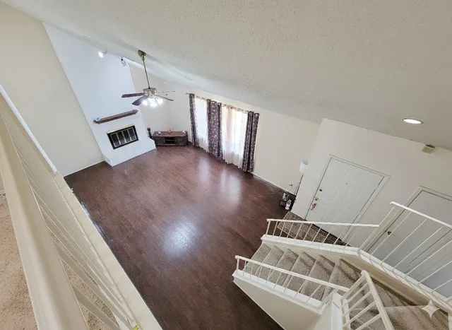 a view of an empty room with wooden floor and windows