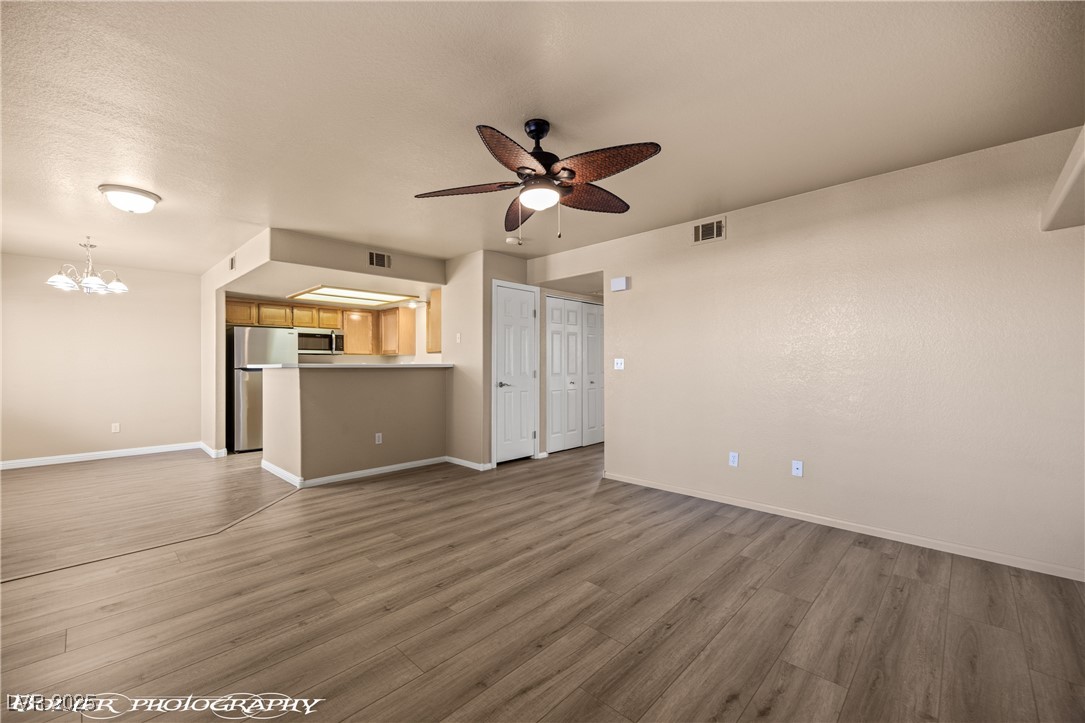 334 Colleen Court, Unit D Mesquite, NV 89027 - Photo 1 of 61 Unfurnished living room with light wood-style flooring, a chandelier, and a ceiling fan