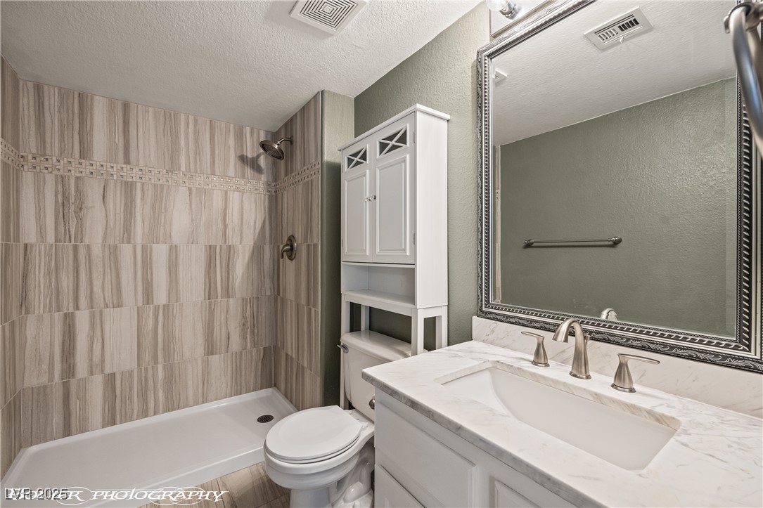 334 Colleen Court, Unit D Mesquite, NV 89027 - Photo 13 of 61 Bathroom with a textured ceiling, vanity, and a shower stall