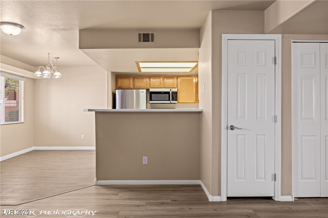 334 Colleen Court, Unit D Mesquite, NV 89027 - Photo 2 of 61 Kitchen featuring a chandelier, light wood finished floors, decorative light fixtures, stainless steel appliances, and a textured ceiling