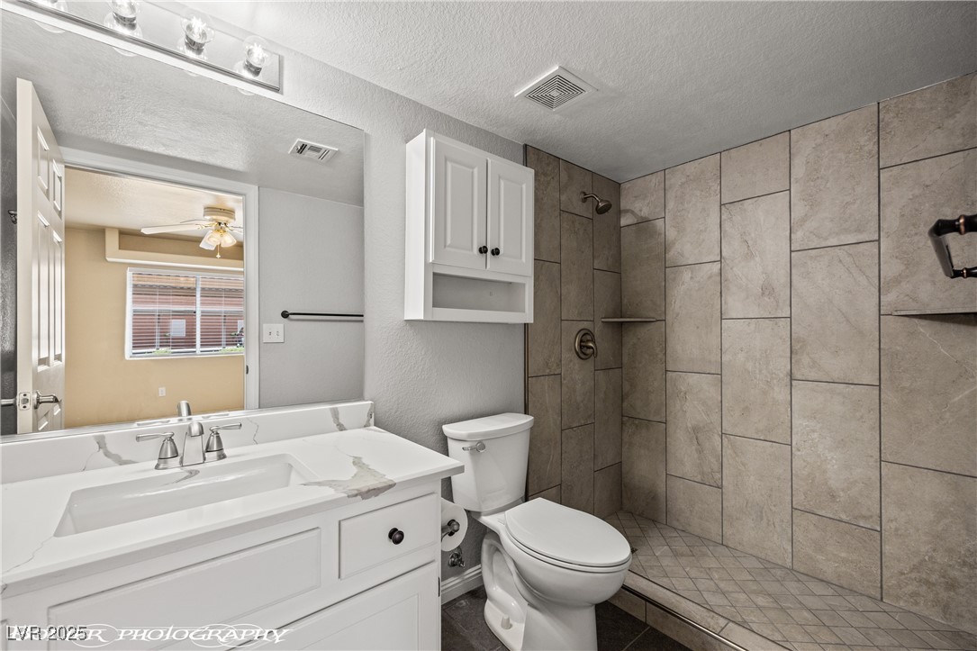 334 Colleen Court, Unit D Mesquite, NV 89027 - Photo 23 of 61 Full bathroom with vanity, a shower stall, a textured ceiling, and dark tile patterned floors