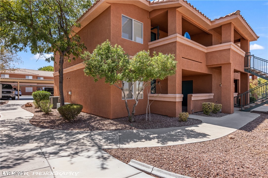 334 Colleen Court, Unit D Mesquite, NV 89027 - Photo 33 of 61 View of property exterior with a tiled roof, stucco siding, a balcony, and stairs
