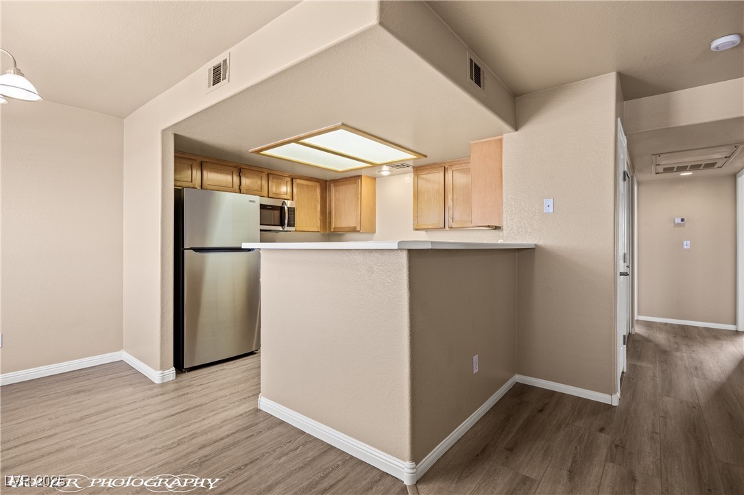 334 Colleen Court, Unit D Mesquite, NV 89027 - Photo 3 of 61 Kitchen with stainless steel appliances, light wood-style floors, light countertops, and a peninsula