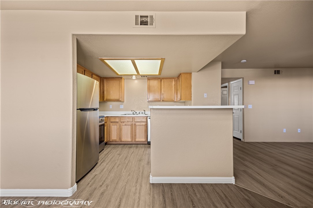334 Colleen Court, Unit D Mesquite, NV 89027 - Photo 6 of 61 Kitchen featuring light countertops, light wood-style flooring, appliances with stainless steel finishes, and light brown cabinets