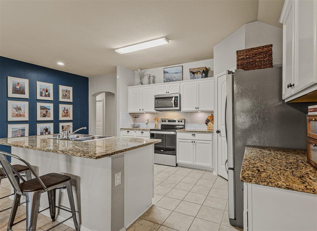 2440 Willard Way Forney, TX 75126 - Photo 11 of 25 a kitchen with stainless steel appliances granite countertop a refrigerator and a stove top oven