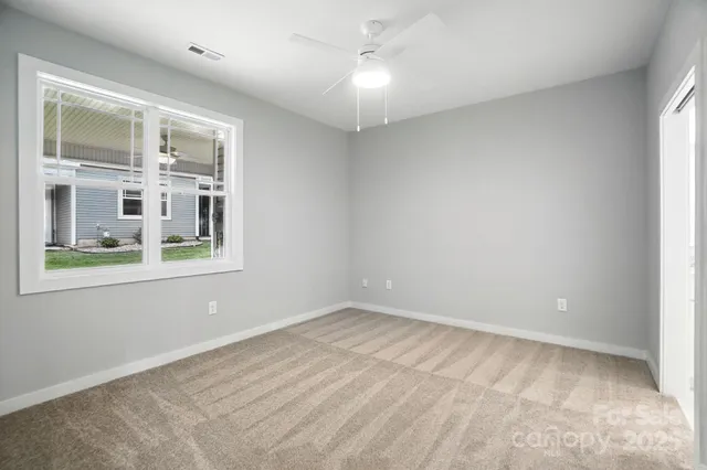an empty room with a windows and chandelier fan
