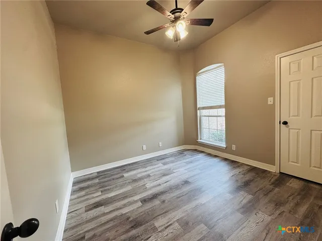 an empty room with wooden floor closet and windows