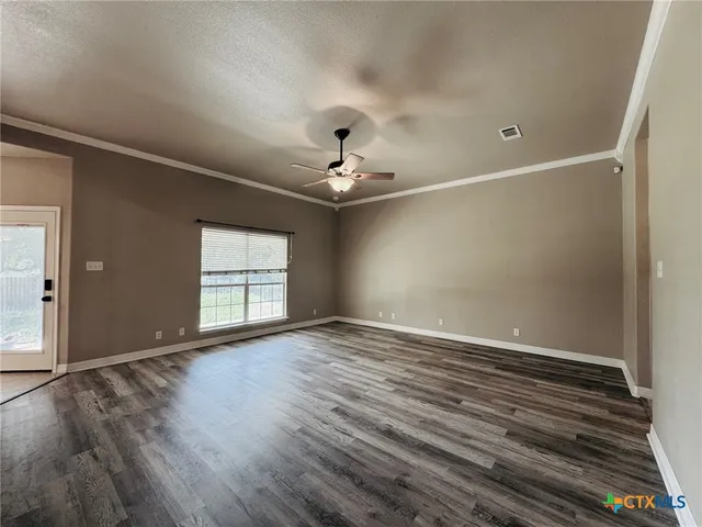 a view of an empty room with a window and wooden floor