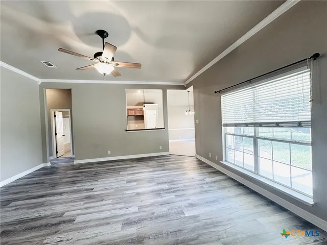 a view of an empty room with a window and wooden floor