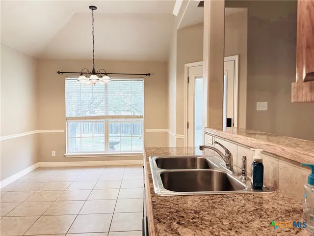 a kitchen with a sink a faucet cabinets and chandelier