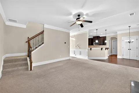 a view of a livingroom with a fireplace a ceiling fan a kitchen and a sink
