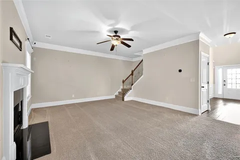 a view of an empty room with a ceiling fan window and fireplace