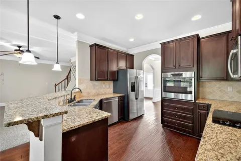 a kitchen with stainless steel appliances granite countertop a refrigerator a stove and a sink with wooden floor