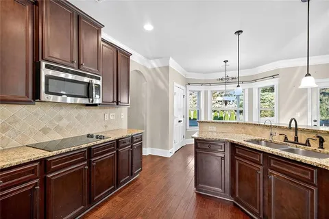 a kitchen with stainless steel appliances granite countertop a sink a stove a microwave and wooden floors