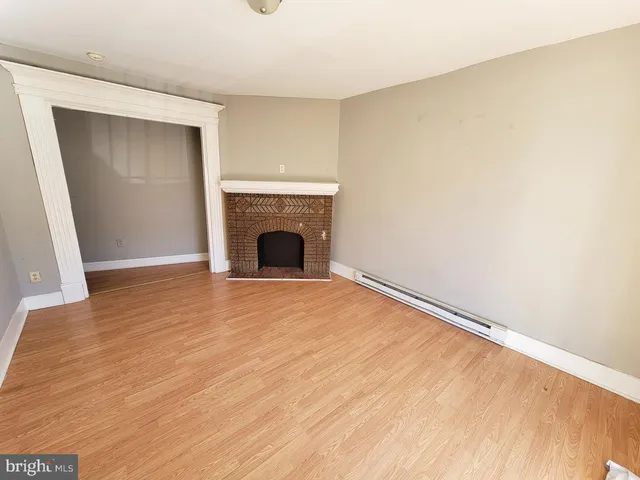 a view of empty room with wooden floor and fireplace