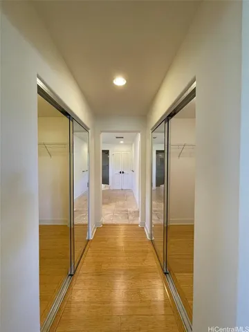 a view of a hallway with wooden floor and a bathroom