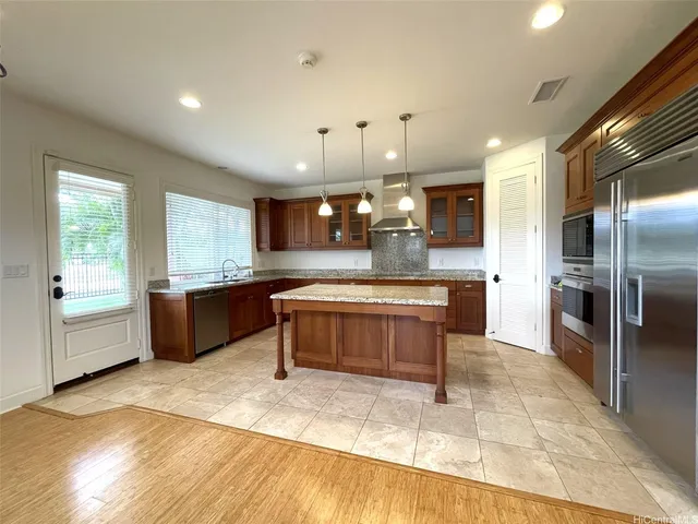 a large kitchen with stainless steel appliances kitchen island granite countertop a large counter top and a refrigerator