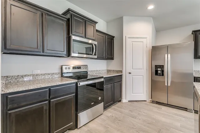 a kitchen with granite countertop a refrigerator stove and microwave