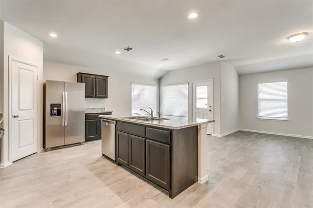 a kitchen with stainless steel appliances granite countertop a refrigerator and a stove top oven