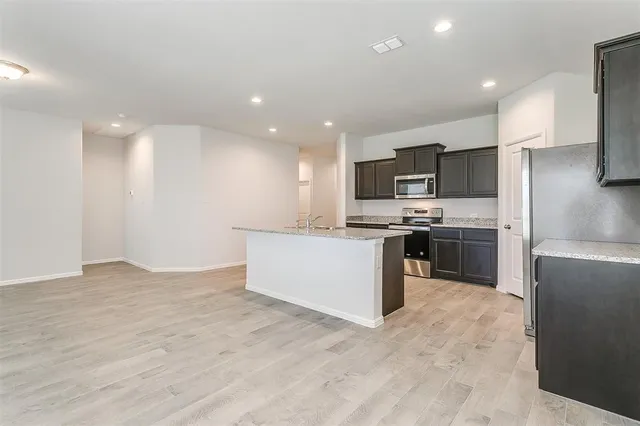 a kitchen with stainless steel appliances kitchen island granite countertop a refrigerator sink and microwave